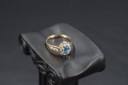 A blue topaz and diamond chip cluster ring having an illusionary mount to cut shoulders on a 9ct