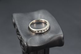 A white metal half eternity ring stamped 18ct having eight diamond chips in square mounts, size