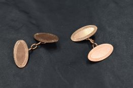 A pair of 9ct rose gold cufflinks having oval panels with engine turned decoration and link