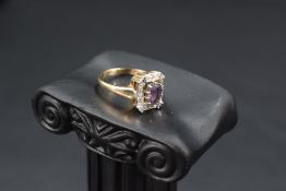 An amethyst ring having a diamond chip set rectangular surround to open shoulders on a 9ct gold