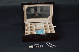 A polished wood style jewellery box having two inner trays and mirror to lid, containing three