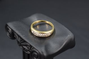 A diamond half eternity ring having seven diamonds in a channel setting on an 18ct gold loop, size O