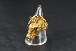 A yellow metal ring stamped 750 in the form of a moulded horse's head having ruby and diamond chip