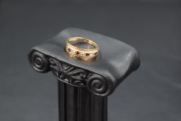 A seven stone garnet and cubic zirconia band ring having cut detail to mount and a 9ct gold loop,