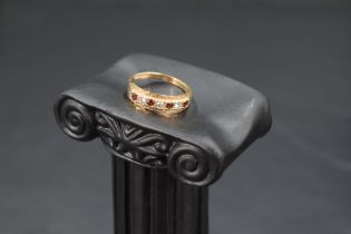 A seven stone garnet and cubic zirconia band ring having cut detail to mount and a 9ct gold loop,