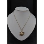 A 9ct gold pendant of knot form having extensive enamelled decoration and central cultured pearl