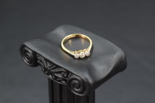 A diamond trilogy ring, total approx 0.128ct in collared mounts on an 18ct gold loop, sizeL & approx