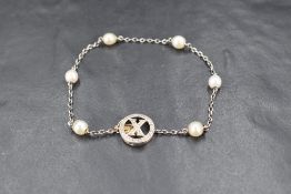 A white metal bracelet having six inset baroque pearls on a fine chain with a diamond set circular