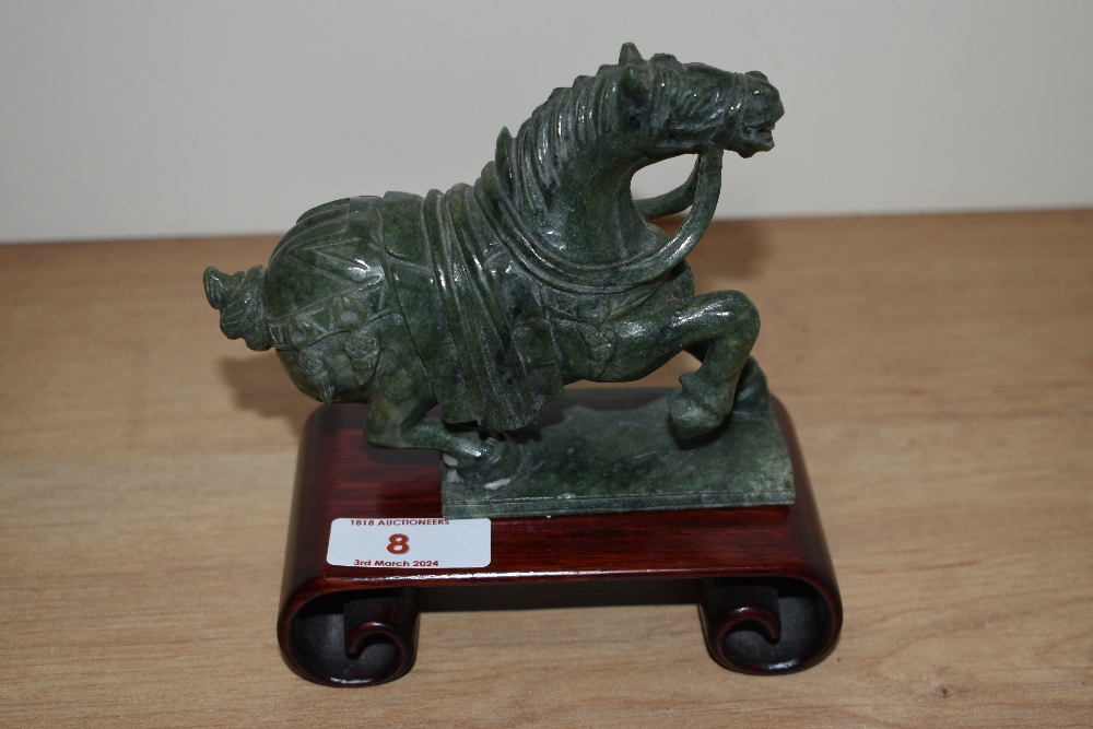 A Chinese green stone rearing horse ornament on hardwood stand, measuring 14cm high overall