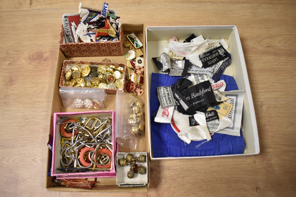 A box of assorted costume jewellery, enamelled and embroidered badges, plus military buttons,