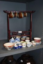 A selection of oriental ceramics,including tea bowls, and miniature cups, some of which are housed
