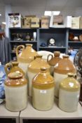 Seven vintage flagons and a stoneware jar, one of interest to S.H Cowell wine and spirit merchant,