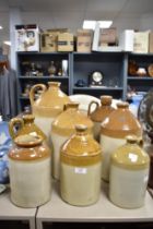 Seven vintage flagons and a stoneware jar, one of interest to S.H Cowell wine and spirit merchant,