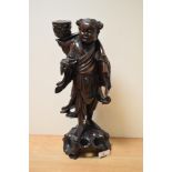 A Chinese carved hardwood Immortal figure with candle sconce, measuring 38cm tall