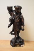 A Chinese carved hardwood Immortal figure with candle sconce, measuring 38cm tall