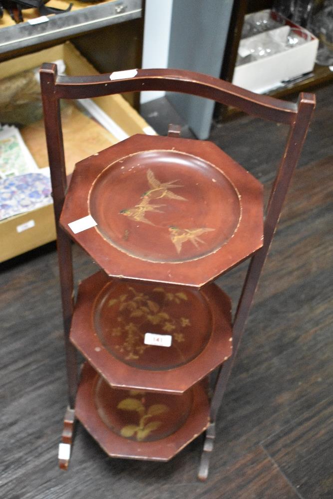 A vintage three tiered wooden cake stand, having gilt painted scenes to each tier.