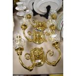 Three brass and glass twin stemmed wall lights.