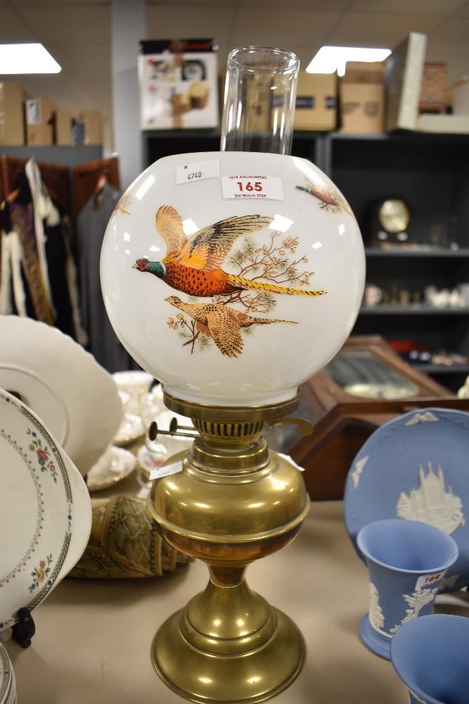 A 20th century brass oil lamp, with glass chimney and mid century opaque shade with pheasants in