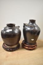 Two glazed earthenware spouted receptacles, one having handle, both with treacle glaze and sat on