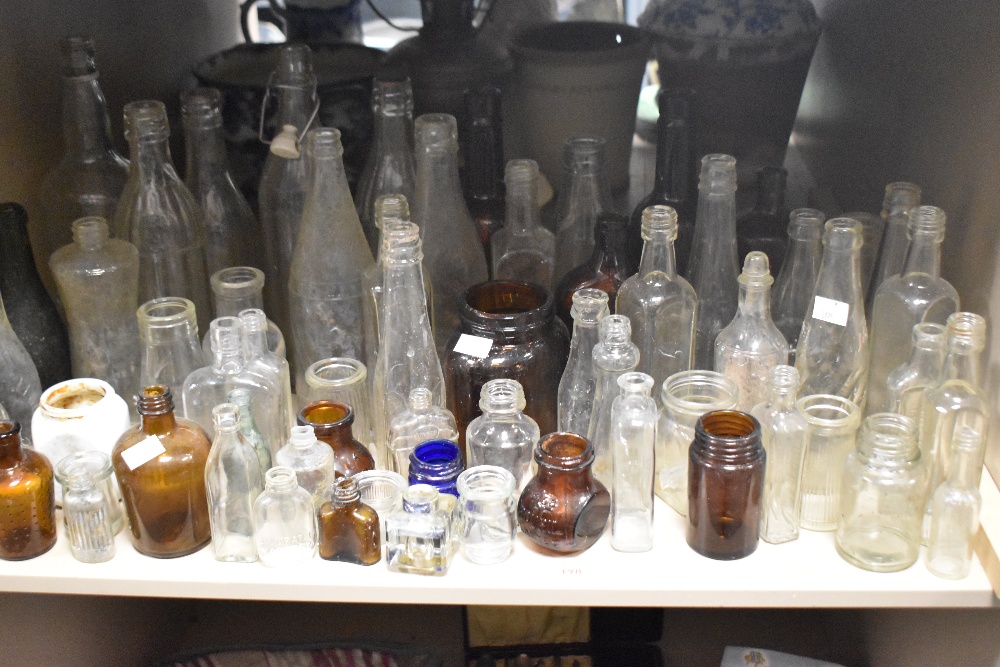 A large collection of vintage glass bottles and jars , including advertising bottles of interest