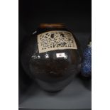 A large 19th/20th Century Chinese pottery liquor jar, against a brown glazed ground, and with