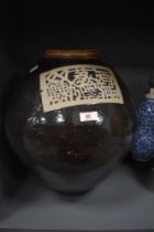 A large 19th/20th Century Chinese pottery liquor jar, against a brown glazed ground, and with