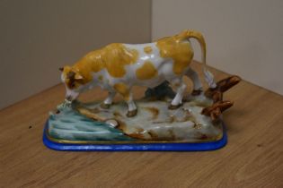 A Continental porcelain cow study, modelled in a naturalistic setting and hand-decorated in