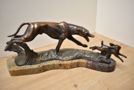 An Art Deco design cast-metal coursing greyhound and rabbit group, of stylistic form and modelled