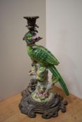 An attractive cast gilt metal and porcelain candlestick, formed as a perched parrot holding a
