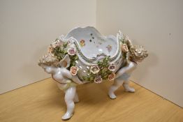 A Dresden porcelain figural centre-piece, formed as three three winged cherubs holding a flower