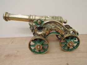 A brass Chinese Dragon design Cannon having spooked wheels, barrel length 38cm, overall length 46cm,