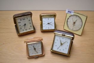A collection of five retro travel alarm clocks.
