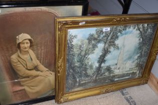 Two pictures, a print of a cathedral with cows to the forefront and a family photograph of a lady in