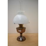 A vintage oil lamp complete with glass shade and chimney.