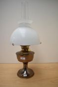 A vintage oil lamp complete with glass shade and chimney.