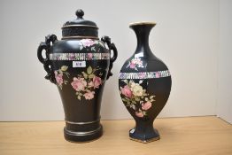 An early 20th century black urn with lid, having floral decoration on black ground, AF and a similar