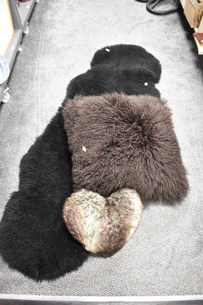 A double sized black sheep skin rug 180cm x 67cm sold along with a large sheep skin fleece cushion