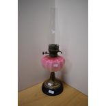 A Victorian brass and coloured glass oil lamp, of traditional design with opaque graduated cranberry