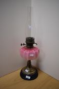 A Victorian brass and coloured glass oil lamp, of traditional design with opaque graduated cranberry