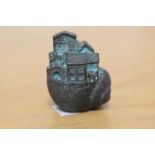 An interesting cast metal paperweight in the form of a house within a snail shell, measuring 5cm