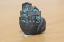 An interesting cast metal paperweight in the form of a house within a snail shell, measuring 5cm