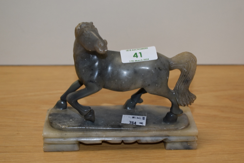 A Chinese soapstone carved horse study, raised on a stepped base, measuring 14cm tall
