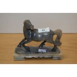 A Chinese soapstone carved horse study, raised on a stepped base, measuring 14cm tall