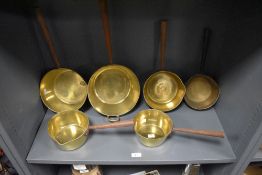 A group of early 19th Century brass saucepans of graduating sizes, the largest measures 50cm long