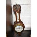 An early 20th century carved oak aneroid barometer, of wheel or banjo form, carved with scroll and