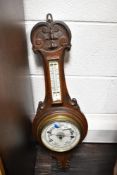 An early 20th century carved oak aneroid barometer, of wheel or banjo form, carved with scroll and