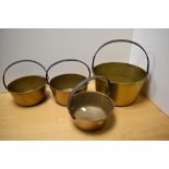 A group of four brass preserve/jam pans, one large and three small, each with iron over handle.