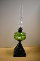 A Victorian oil lamp, with moulded green glass reservoir and painted cast iron base, measuring