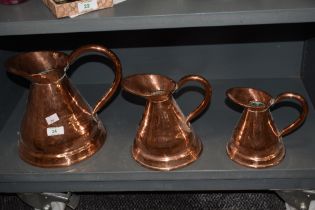 Three Victorian planished copper pitchers, of graduating sizes, the largest measures 26cm tall