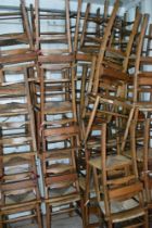Twenty eight traditional chapel chairs having book shelf to back and rush seats